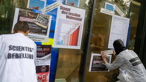 Aktivisten der Klimabewegung "Scientist Rebellion" kleben Plakate mit Fakten über die Erderwärumg an eine Filiale der Deutschen Bank in München. 