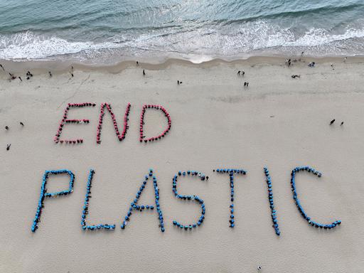 An einem Strand sind die Worte END PLASTIC mit Plastikmüll in den Sand gelegt worden