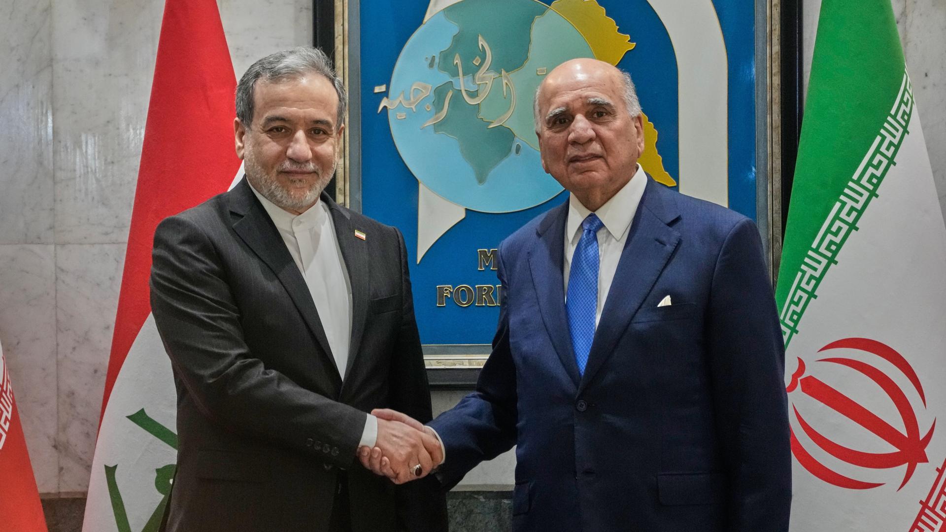Iraks Außenminister Fouad Hussein schüttelt die Hand seines iranischen Amtskollegen Abbas Araghchi bei einem Besuch in Bagdad.