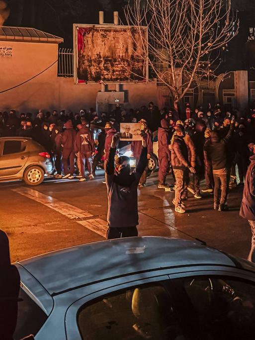 Menschen versammeln sich während einer Protestaktion in Teheran und blockieren dabei eine Straße. 