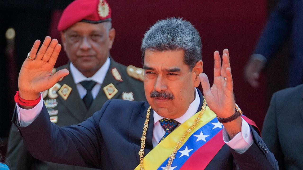 Nicolas Maduro hebt bei seiner Vereidigung beide Hände, hinter ihm steht ein Mitglied der Armee in Venezuela