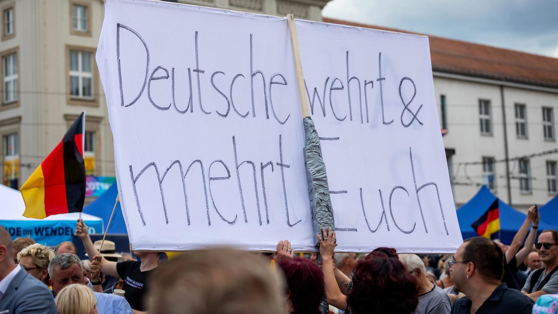 Ein Besucher einer AfD-Wahlkampfveranstaltung hält ein Transparent mit der Aufschrift "Deutsche wehrt und mehr Euch" in die Höhe.