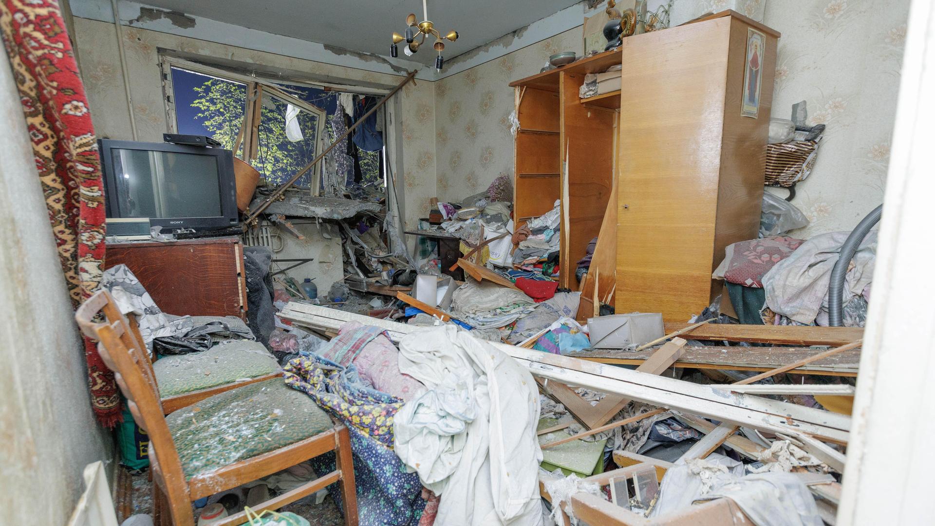 Blick in eine durch russische Angriffe zerstörte Wohnung in Charkiw. Die Fenster sind geborsten, die Möbel zertrümmert