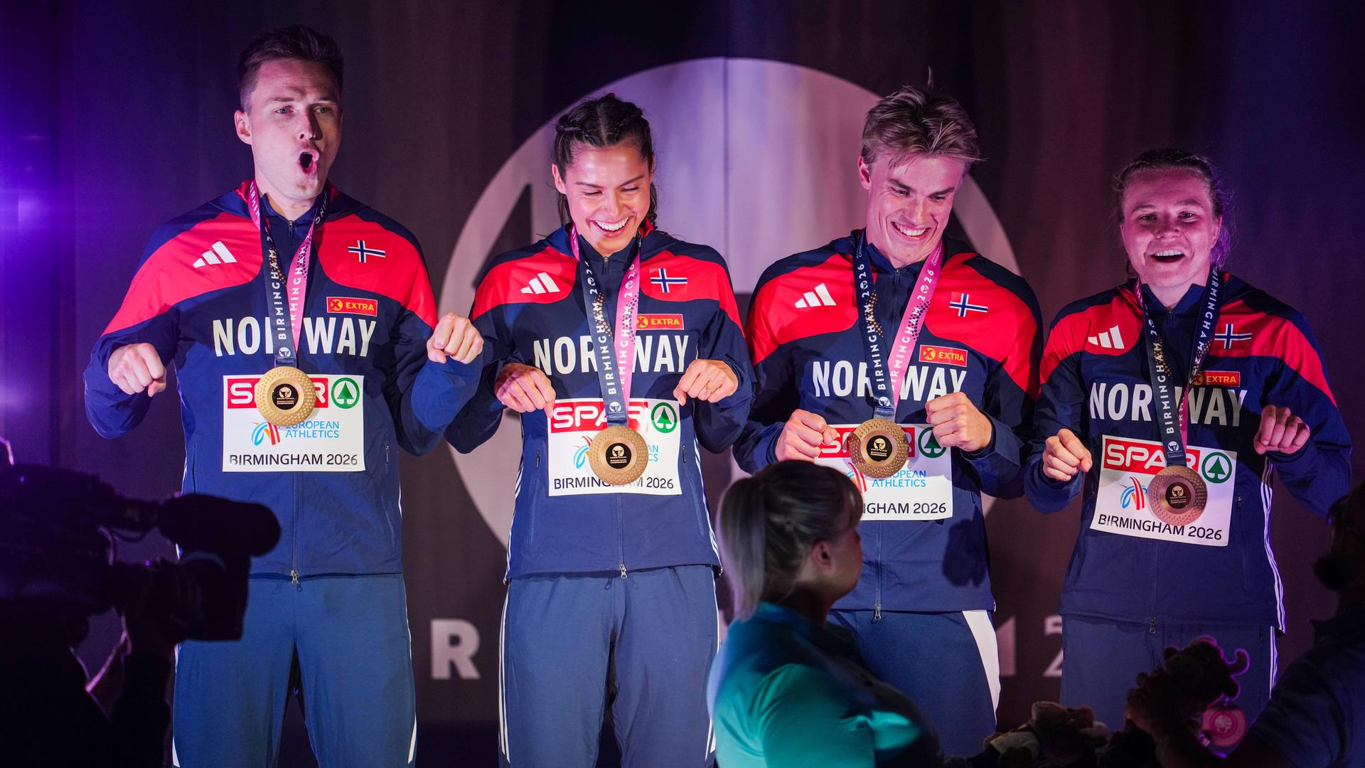 Zwei Männer und zwei Frauen stehen nebeneinander. Sie haben Goldmedaillen um den Hals und lachen. Sie tragen Trikots mit dem Aufdruck "Norway" - also "Norwegen". Zwei Männer und zwei Frauen stehen nebeneinander. Sie haben Goldmedaillen um den Hals und lachen. Sie tragen Trikots mit dem Aufdruck "Norway" - also "Norwegen".