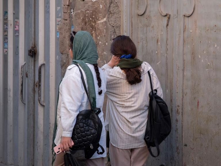 Rückansicht zweier Frauen auf einer Straße in Teheran: Die eine trägt das Kopftuch locker, die andere nur als Halstuch.