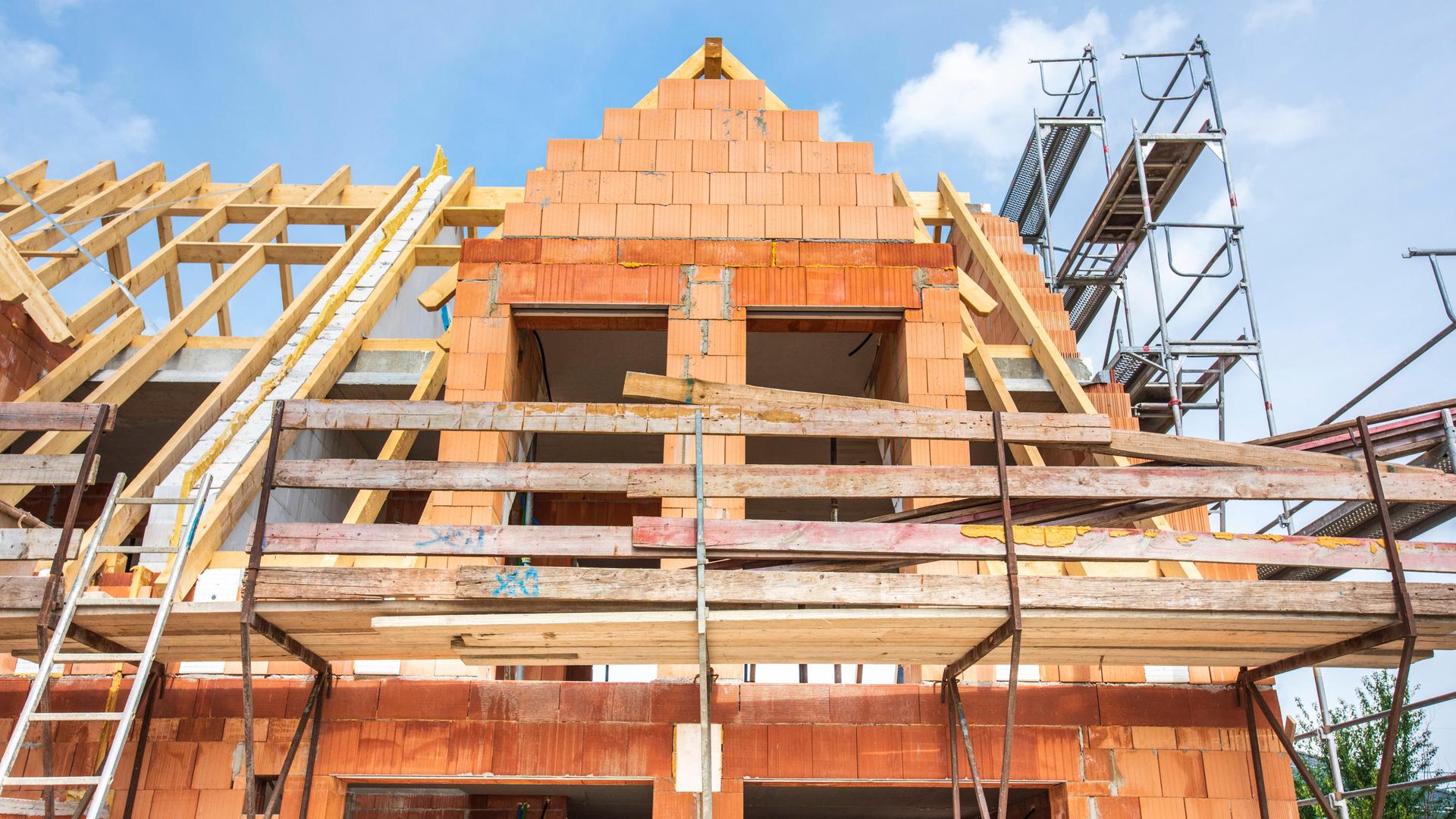 Der Rohbau von einem Wohnhaus im Neubau wird mit Ziegelsteinen gemauert, als Symbolbild für Wohnungsbau und Wohnpolitik