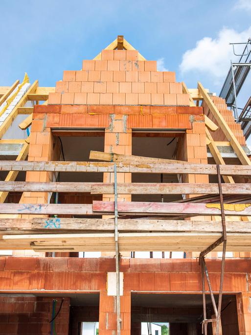 Der Rohbau von einem Wohnhaus im Neubau wird mit Ziegelsteinen gemauert, als Symbolbild für Wohnungsbau und Wohnpolitik