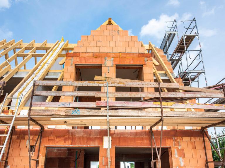 Der Rohbau von einem Wohnhaus im Neubau wird mit Ziegelsteinen gemauert, als Symbolbild für Wohnungsbau und Wohnpolitik