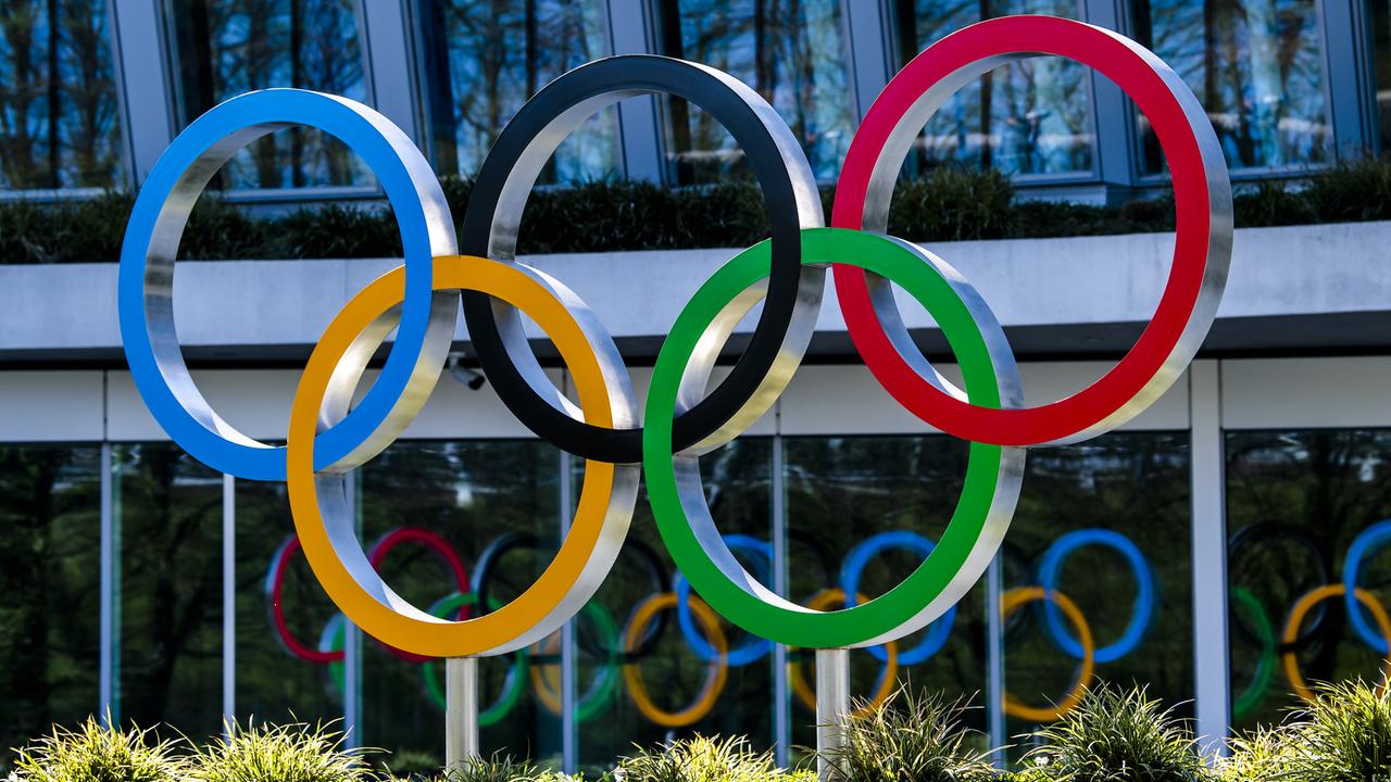 Die olympischen Ringe in den Farben Blau, Schwarz, Rot, Gelb und Grün sind vor einem Gebäude angebracht.