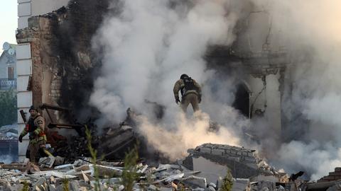 Ein Feuerwehrmann geht durch den Qualm eines brennenden Hauses, nach russischen Beschuss