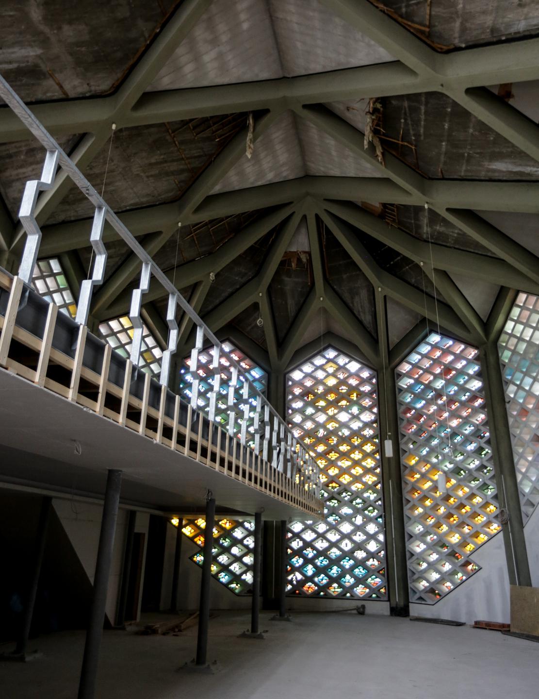 Innenraum der ehemaligen Kapernaum-Kirche in Hamburg Horn, durch bunte Facettenfenster fällt Licht hinein, links im Bild: die neu eingebaute Empore für Frauen zur künftigen Nutzung des Gebäudes als Moschee.