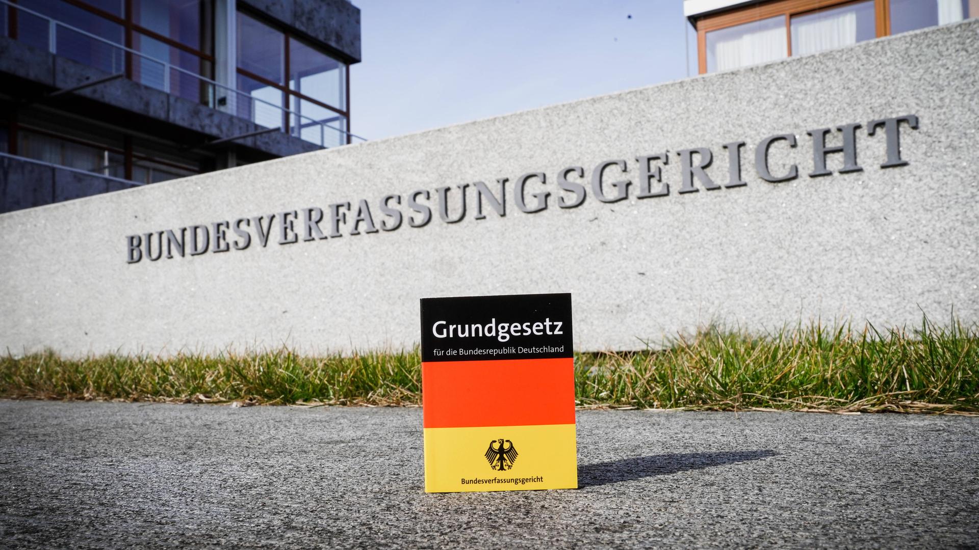 Das Grundgesetz in den Farben der Deutschlandflagge steht vor dem Eingangsschild des Bundesverfassungsgerichts.