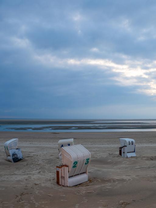 Bei bedecktem Wetter stehen Strandkörbe am Strand von Borkum. Bei bedecktem Wetter stehen Strandkörbe am Strand von Borkum.