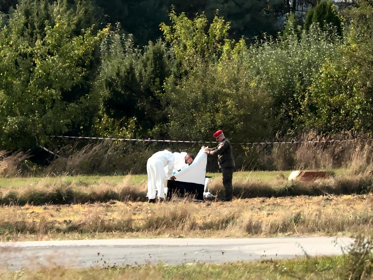 Drei Männer prüfen ein Drohnenwrack nahe dem Dorf Mniszkow in Polen.