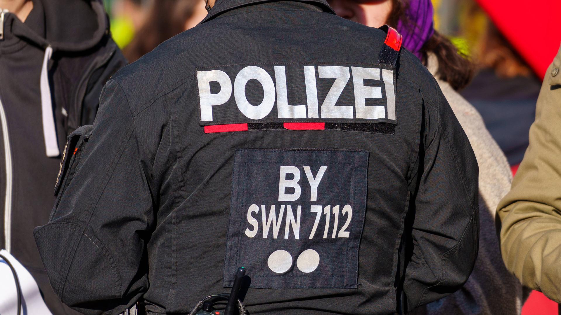 Schriftzug Polizei auf dem Rücken der Uniform eines Polizeibeamten. 
