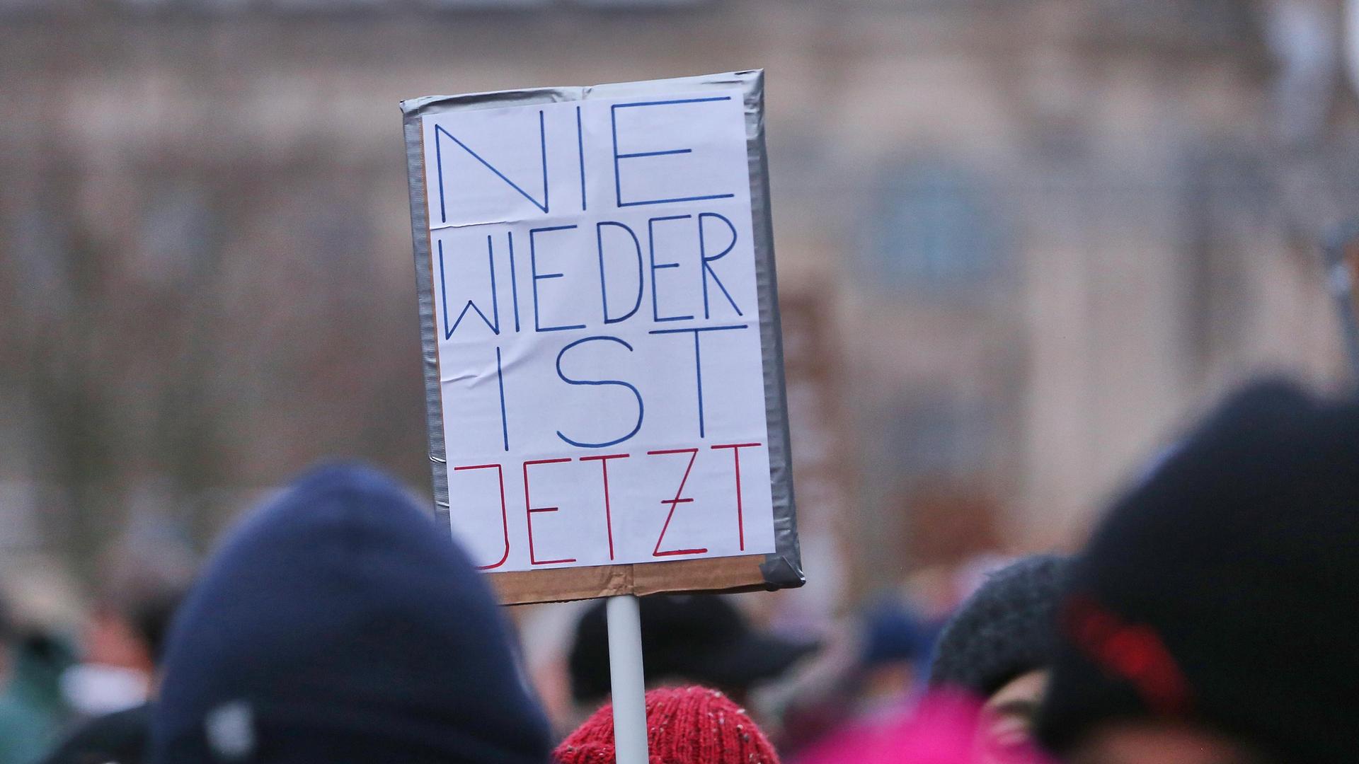 Bei der Demo unter dem Motto "Aufstand der Anständigen - Wir sind die Brandmauer" auf der Berliner Reichstagswiese ist über den Köpfen von Teilnehmern ein Protestschild mit der Aufschrift "Nie wieder ist jetzt" zu sehen. Bei der Demo unter dem Motto "Aufstand der Anständigen - Wir sind die Brandmauer" auf der Berliner Reichstagswiese ist über den Köpfen von Teilnehmern ein Protestschild mit der Aufschrift "Nie wieder ist jetzt" zu sehen.