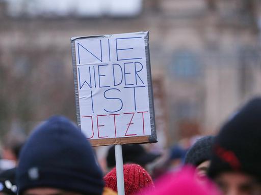 Bei der Demo unter dem Motto "Aufstand der Anständigen - Wir sind die Brandmauer" auf der Berliner Reichstagswiese ist über den Köpfen von Teilnehmern ein Protestschild mit der Aufschrift "Nie wieder ist jetzt" zu sehen.