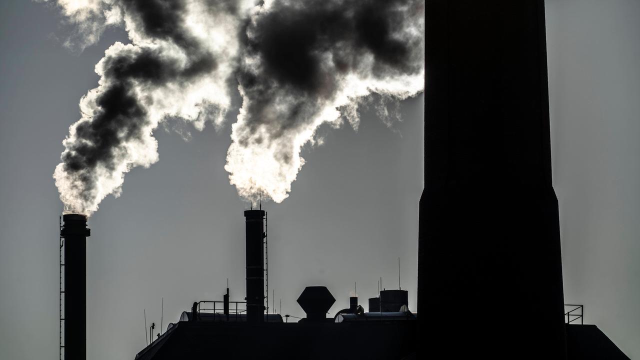 Aus zwei Schornsteinen eines Gaskraftwerks steigt vor einem grauen Abendhimmel weiß-grauer Rauch auf.