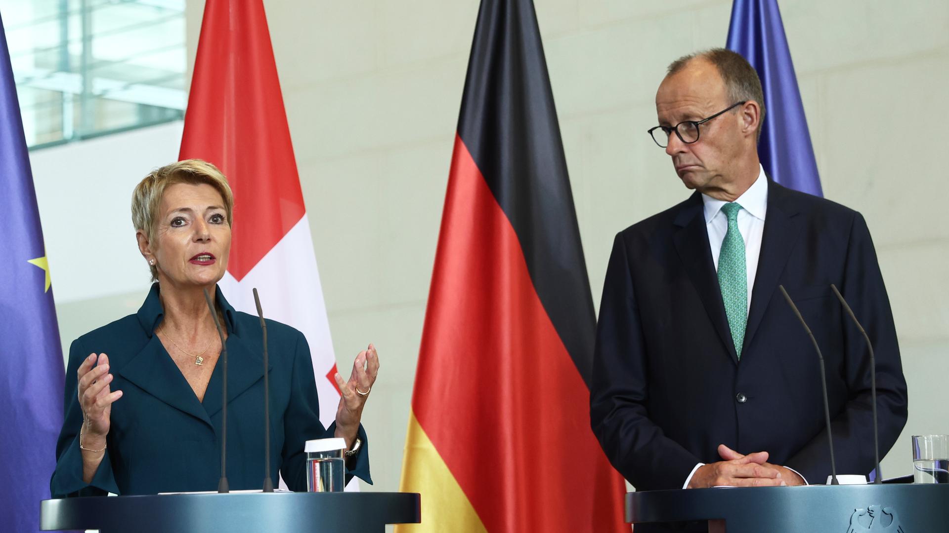 Die Schweizer Bundespräsidentin Karin Keller-Sutter und Bundeskanzler Friedrich Merz stehen an Rednerpulten.