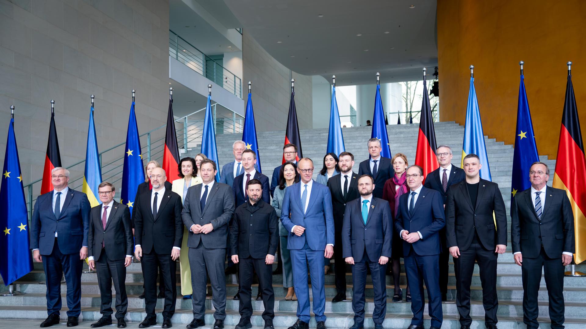 Viele Menschen in Anzügen stehen vor einer Reihe von Fahnen. Viele Menschen in Anzügen stehen vor einer Reihe von Fahnen.