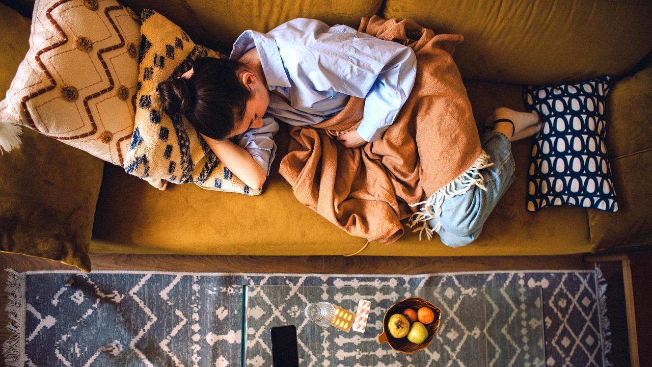 Eine junge Frau liegt auf dem Sofa mit einer Decke