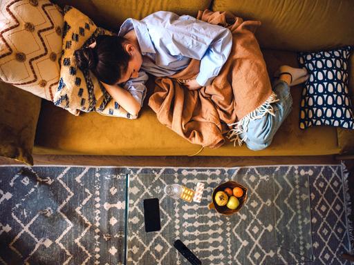 Eine junge Frau liegt auf dem Sofa mit einer Decke Eine junge Frau liegt auf dem Sofa mit einer Decke