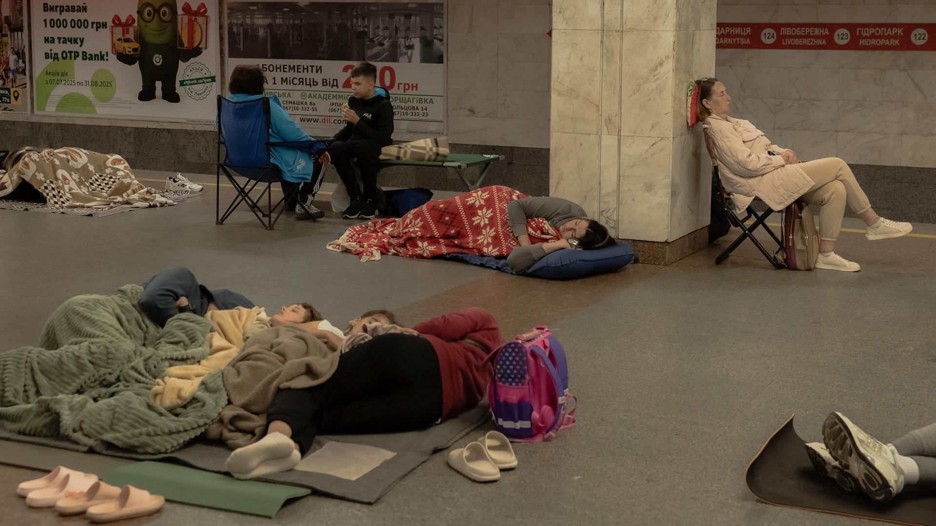 Menschen sitzen oder liegen in einer U-Bahn-Station in Kiew.