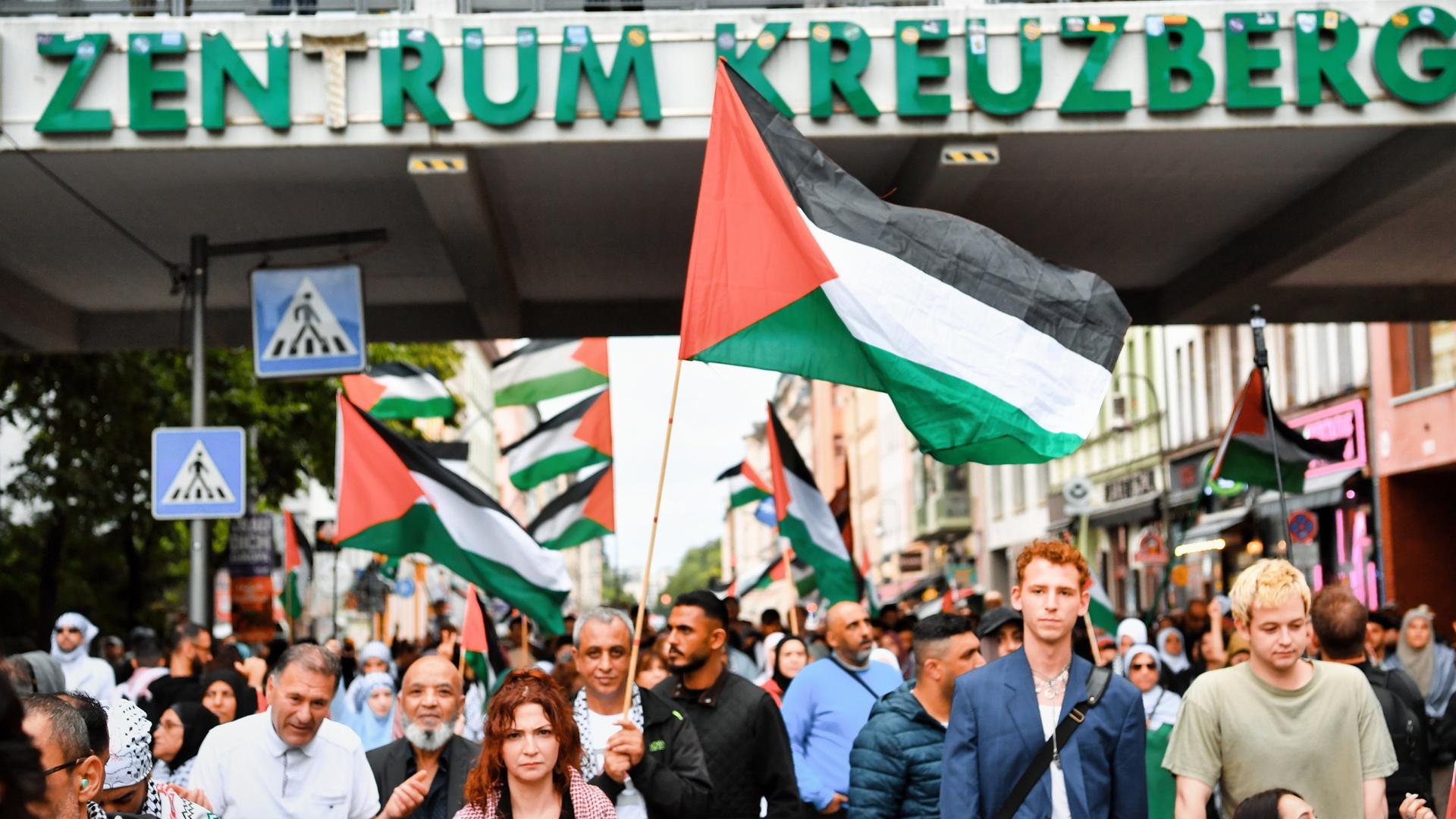 Teilnehmer gehen mit palästinensischen Fahnen bei einer pro-palästinensische Demonstration über eine Straße in Kreuzberg. Teilnehmer gehen mit palästinensischen Fahnen bei einer pro-palästinensische Demonstration über eine Straße in Kreuzberg.