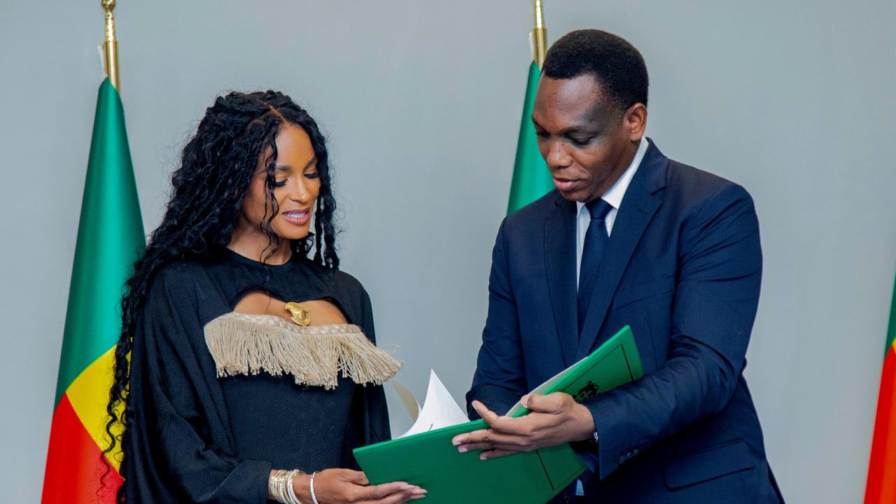Yvon Detchenou, Benins Justizminister (rechts im Bild), überreicht der Sängerin Ciara im Rahmen einer Zeremonie in Cotonou die Staatsbürgerschaftsurkunde.