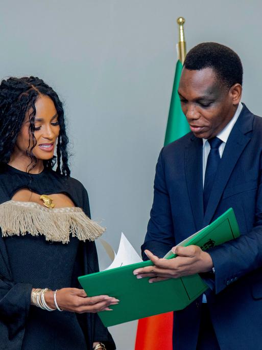 Yvon Detchenou, Benins Justizminister (rechts im Bild), überreicht der Sängerin Ciara im Rahmen einer Zeremonie in Cotonou die Staatsbürgerschaftsurkunde.