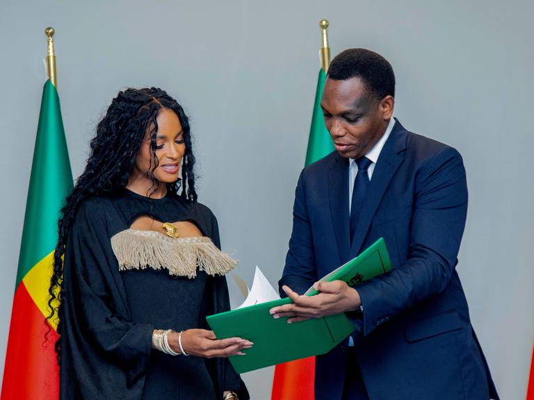 Yvon Detchenou, Benins Justizminister (rechts im Bild), überreicht der Sängerin Ciara im Rahmen einer Zeremonie in Cotonou die Staatsbürgerschaftsurkunde.