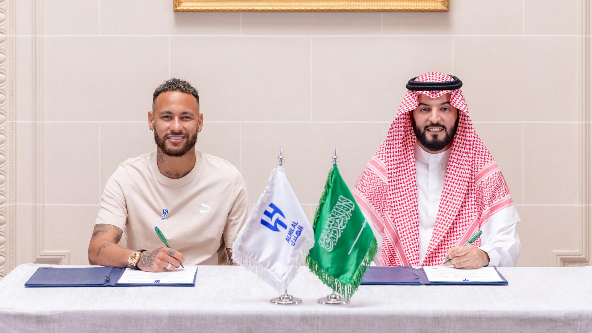 Der Brasilianische Fußballstar Neymar (l.) und Al-Hilals Präsident Fahad bin Nafel (re.) posieren für ein Foto, als Neymar seinen Zweijahresvertrag unterschreibt. 