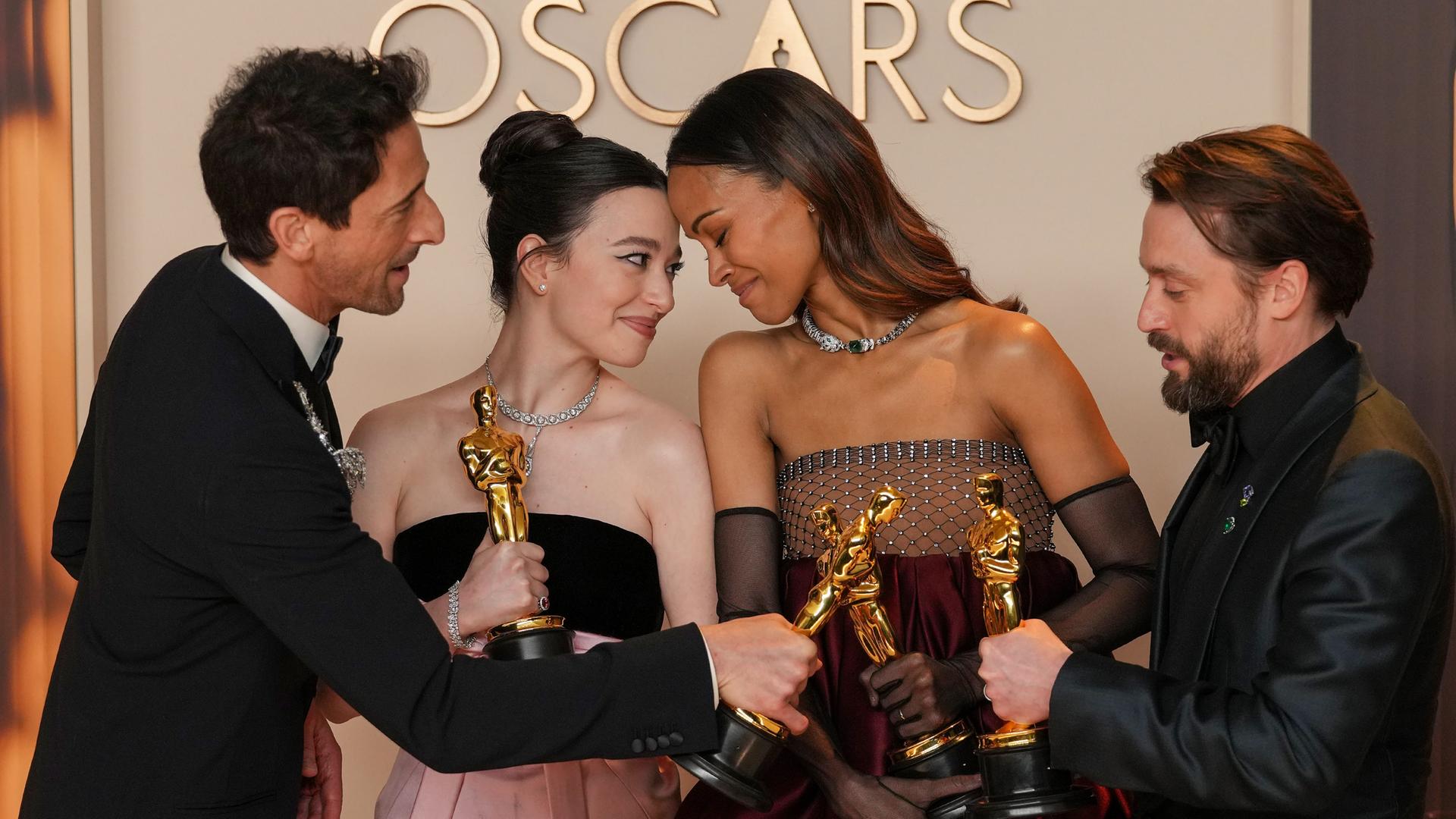 Adrien Brody, Mikey Madison, Zoe Saldaña und Kieran Culkin stehen nebeneinander mit ihren Oscars in der Hand.