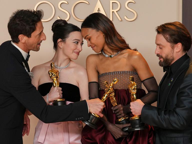 Adrien Brody, Mikey Madison, Zoe Saldaña und Kieran Culkin stehen nebeneinander mit ihren Oscars in der Hand.