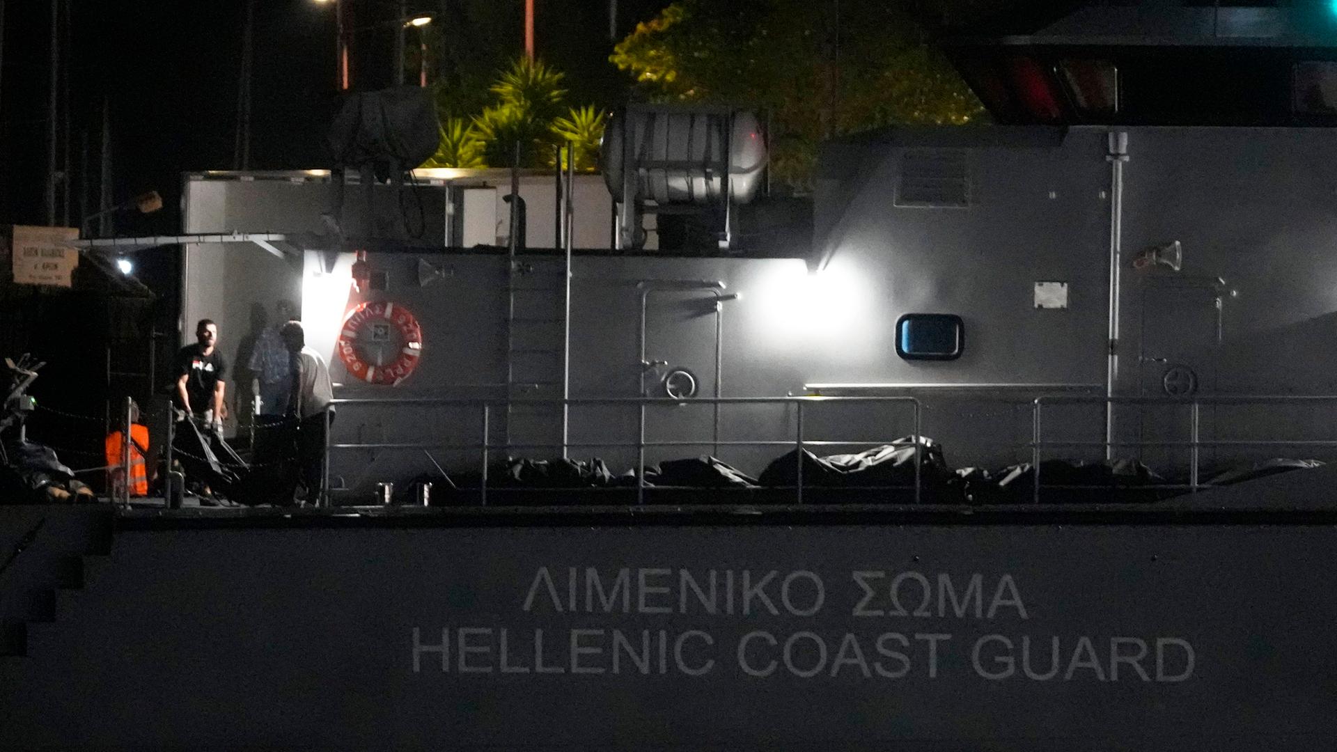 Griechenland, Kalamata: Rettungskräfte tragen Leichen von einem Schiff der Küstenwache in einen Kühlwagen im Hafen von Kalamata, etwa 240 Kilometer südwestlich von Athen.