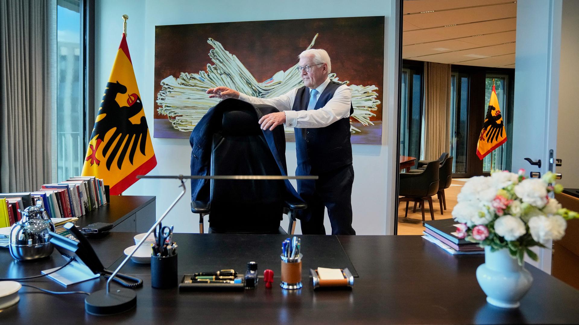 Frank-Walter Steinmeier steht hinter seinem Schreibtisch und legt seine Anzugjacke um die Lehne seines Schreibtischstuhls. Frank-Walter Steinmeier steht hinter seinem Schreibtisch und legt seine Anzugjacke um die Lehne seines Schreibtischstuhls.