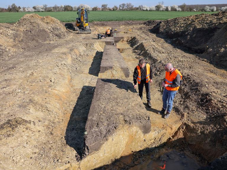 Stefan Tesselow, Grabungsleiter, und Christoph Heiermann (r), Referatsleiter am Landesamt für Archäologie Sachsen, sprechen über eine Ausgrabung auf dem künftigen Trassenverlauf einer Fernwärmeleitung bei Leipzig. 