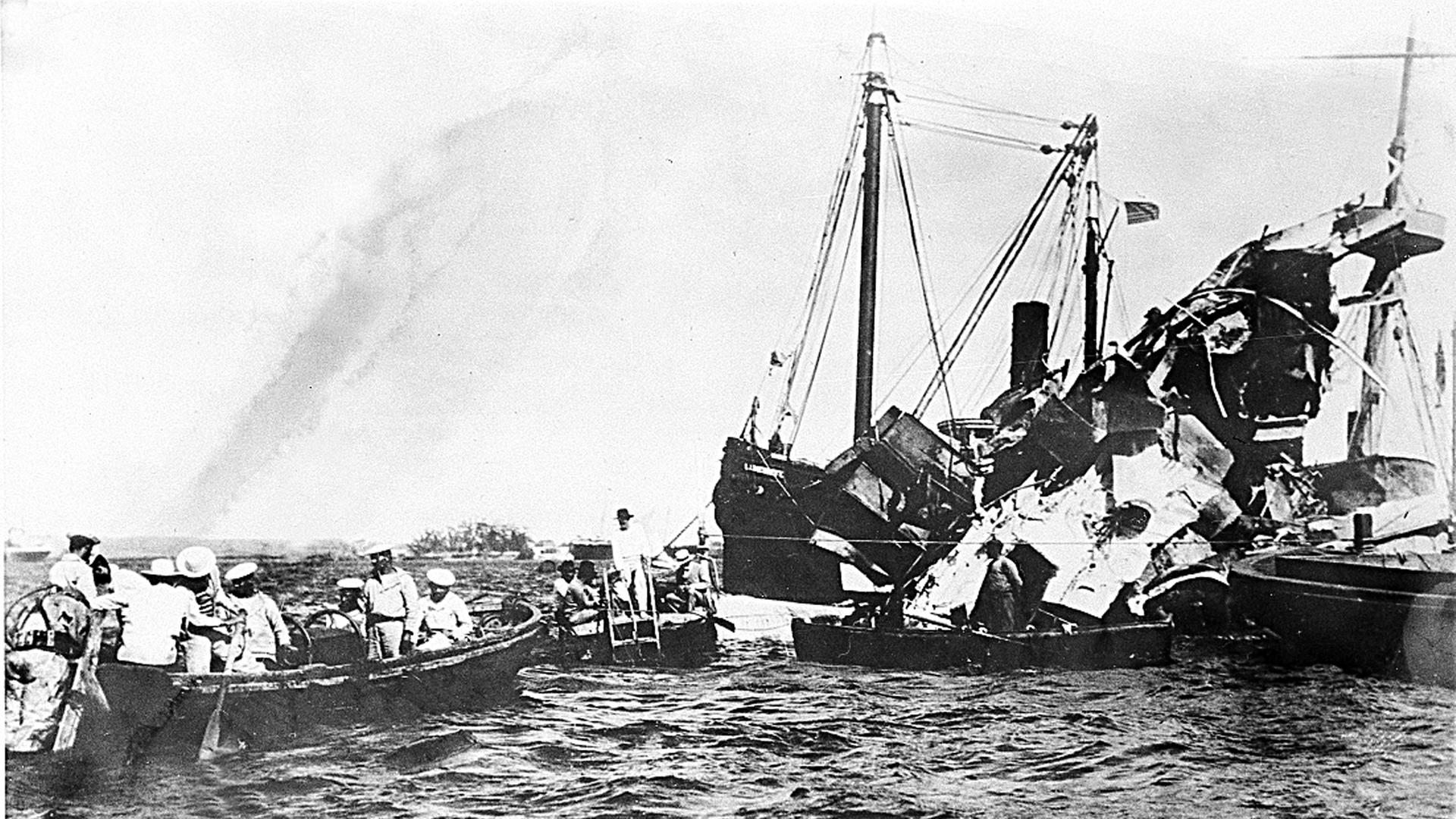 Eine Schwarz-Weiß-Fotografie zeigt Rettungsboote neben dem sinkenden Schlachtschiff USS Maine Eine Schwarz-Weiß-Fotografie zeigt Rettungsboote neben dem sinkenden Schlachtschiff USS Maine