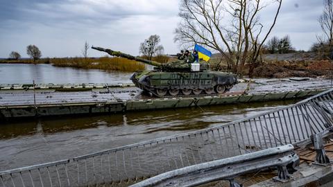Ein Panzer überquert auf einer Behelfsbrücke einen Fluss.