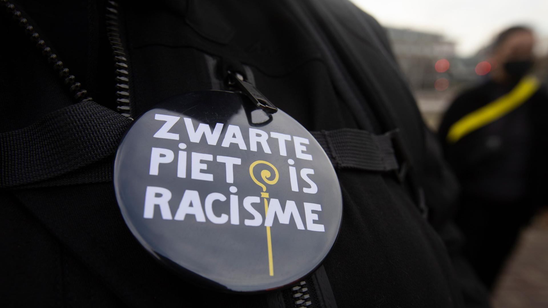 Eine Frau trägt im November 2020 einen Button mit der Aufschrift "Black Pete Is Racism" (Schwarzer Peter ist Rassismus) während einer Demonstration in Breda, Südniederlande.