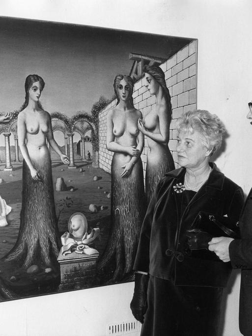 Peggy Guggenheim 1964 bei einer Ausstellung ihrer Sammlung in London mit dem Direktor der Tate Gallery, Norman Reid vor dem Gemälde "The Break of DAY von Paul Delvaux.