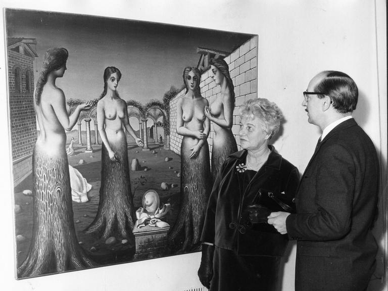 Peggy Guggenheim 1964 bei einer Ausstellung ihrer Sammlung in London mit dem Direktor der Tate Gallery, Norman Reid vor dem Gemälde "The Break of DAY von Paul Delvaux.