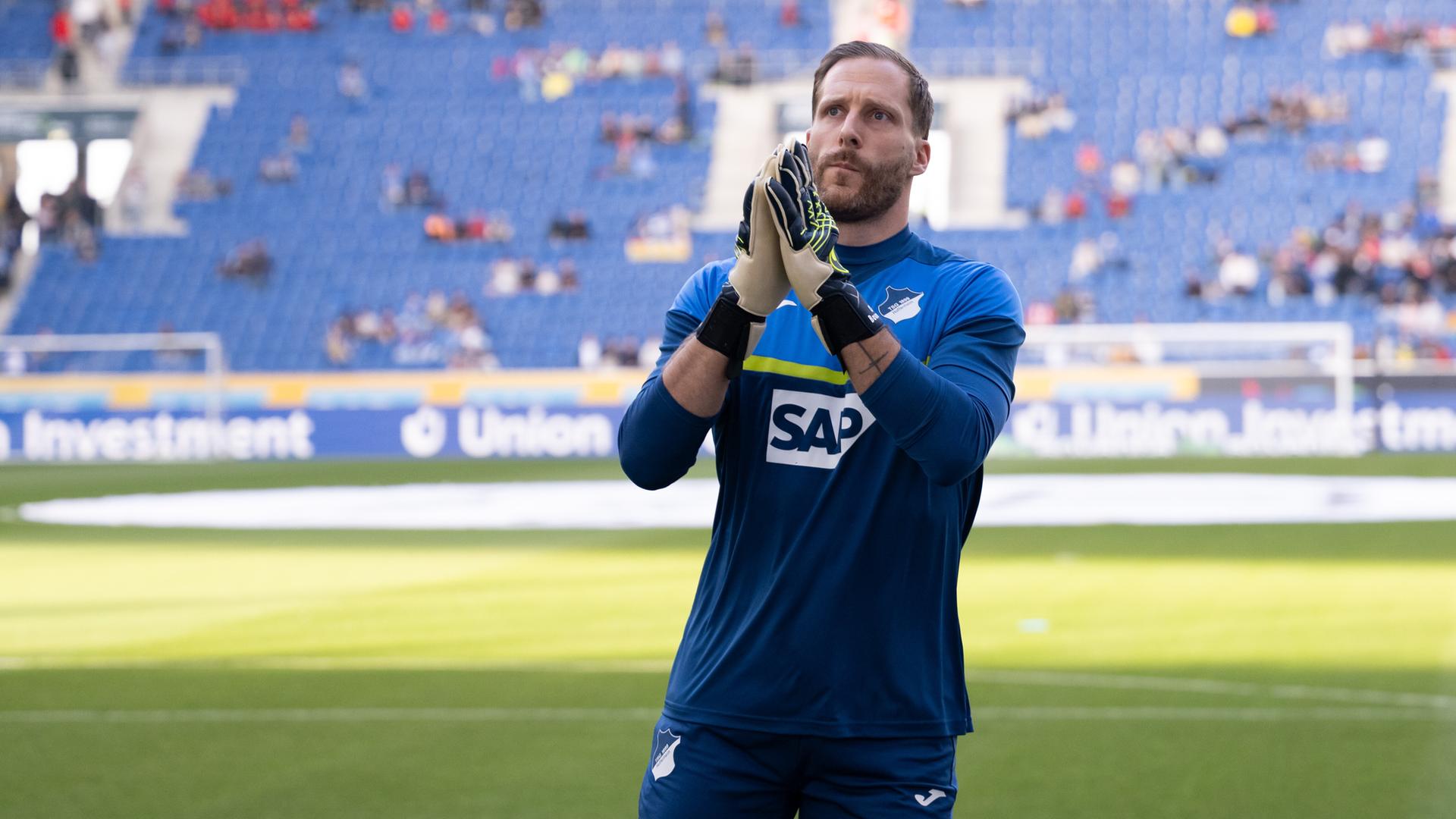 Torwart Oliver Baumann im Trikot der TSG 1899 Hoffenheim steht auf dem Spielfeld und bedankt sich bei den Fans.