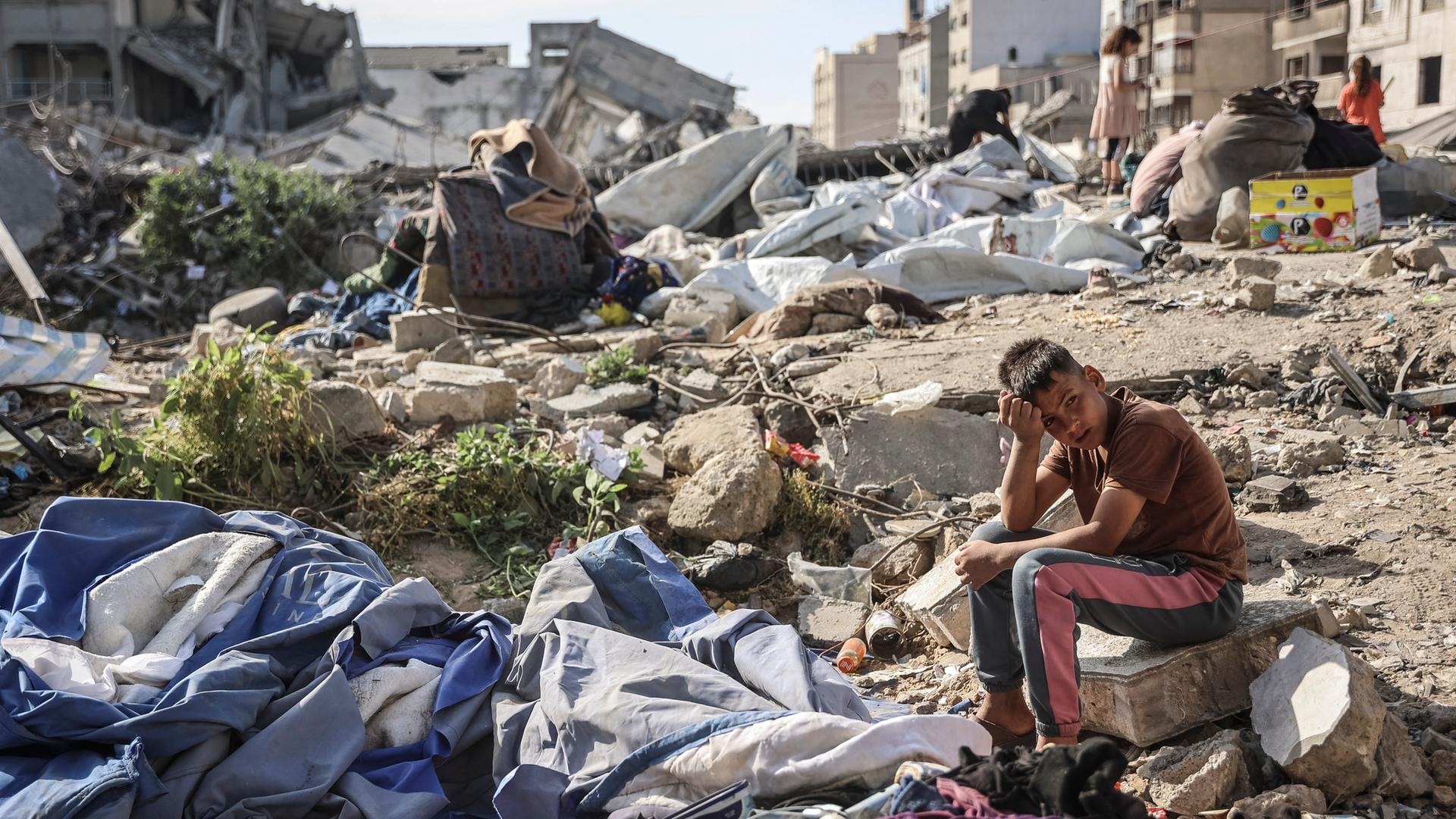Ein Junge sitzt nach einem israelischen Luftangriff auf Gaza inmitten von Trümmern.