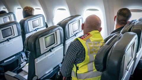 Ein Polizeibeamter sitzt neben einem Afghanen in einem Flugzeug.
