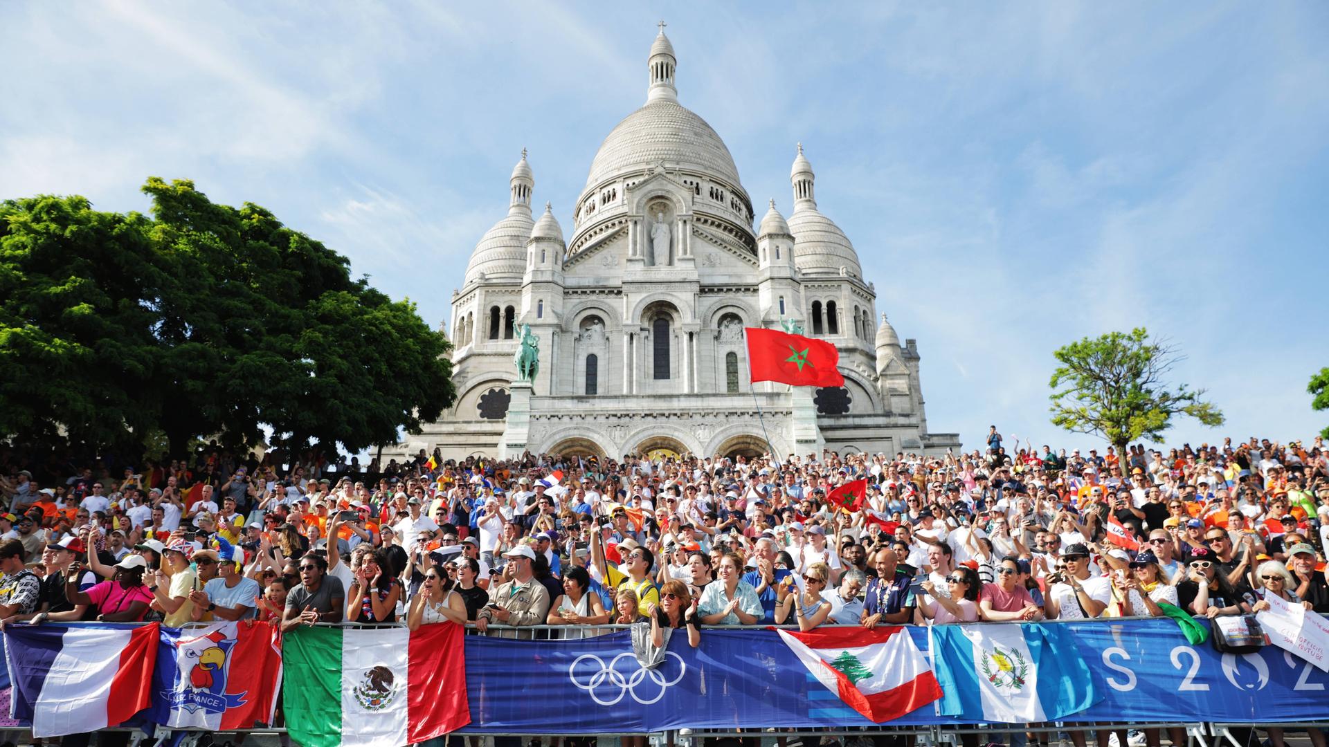 Bei den Olympischen Spielen 2024 in Paris stehen Fans an der Straßenrad-Rennstrecke, die durch Montmartre führt.