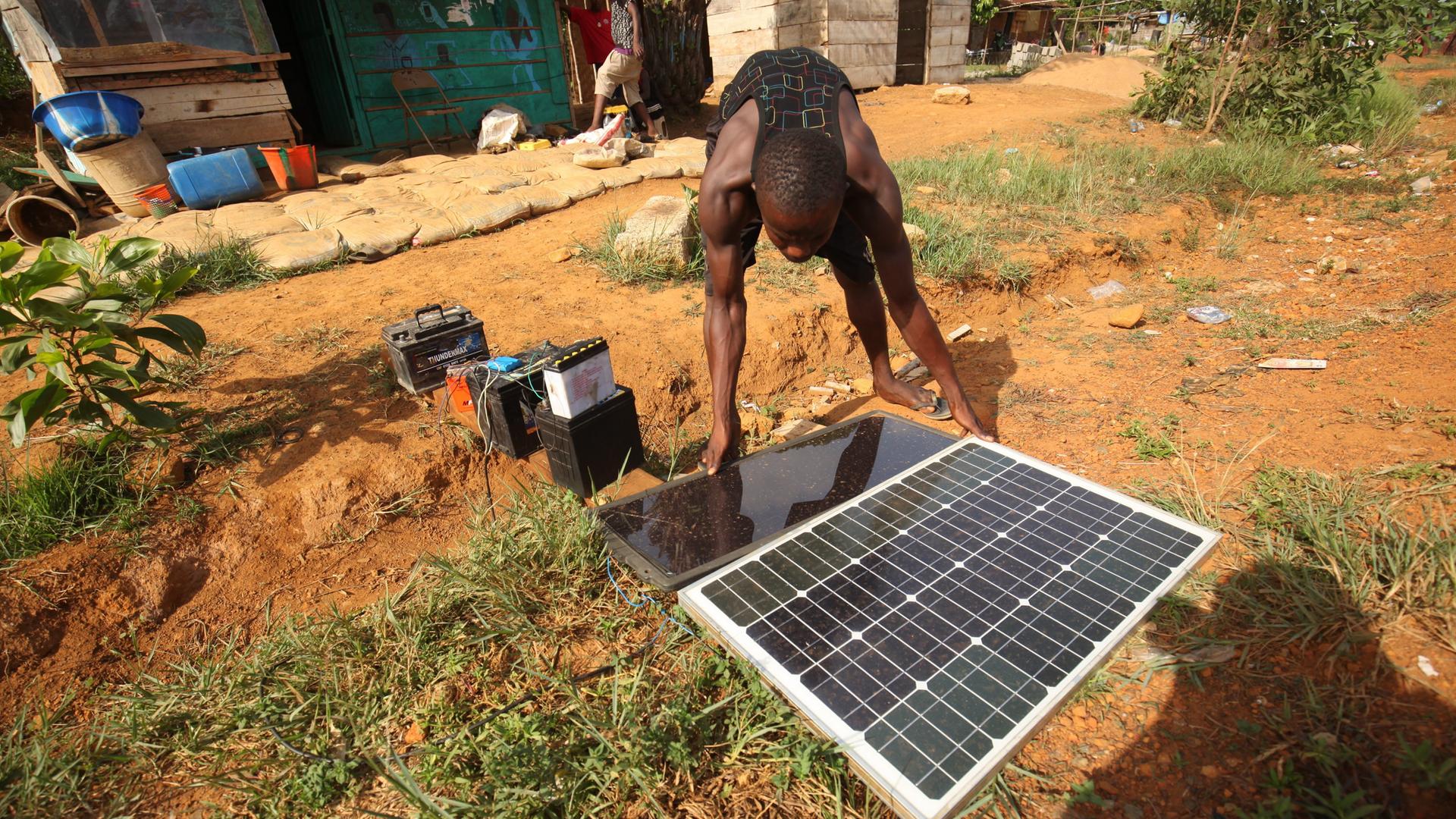 Ein Mann installiert ein Solar-Panel, das am Boden liegt.