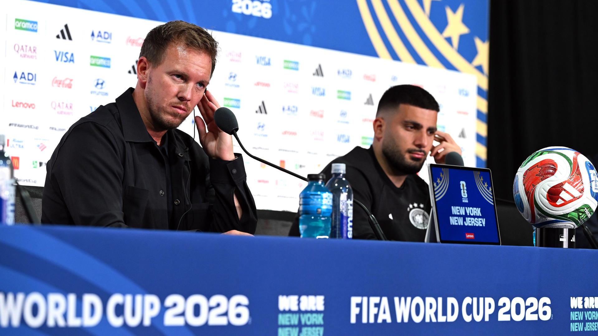 Pressekonferenz vor dem letzten Gruppenspiel gegen Ecuador: Bundestrainer Julian Nagelsmann (l) und Deniz Undav sitzen auf dem Podium vor einer Werbewand und hören konzentriert zu.
      