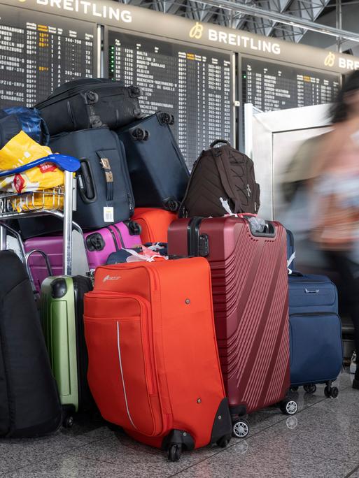 Ein Stapel von Koffern steht in eine Flughafenhalle.