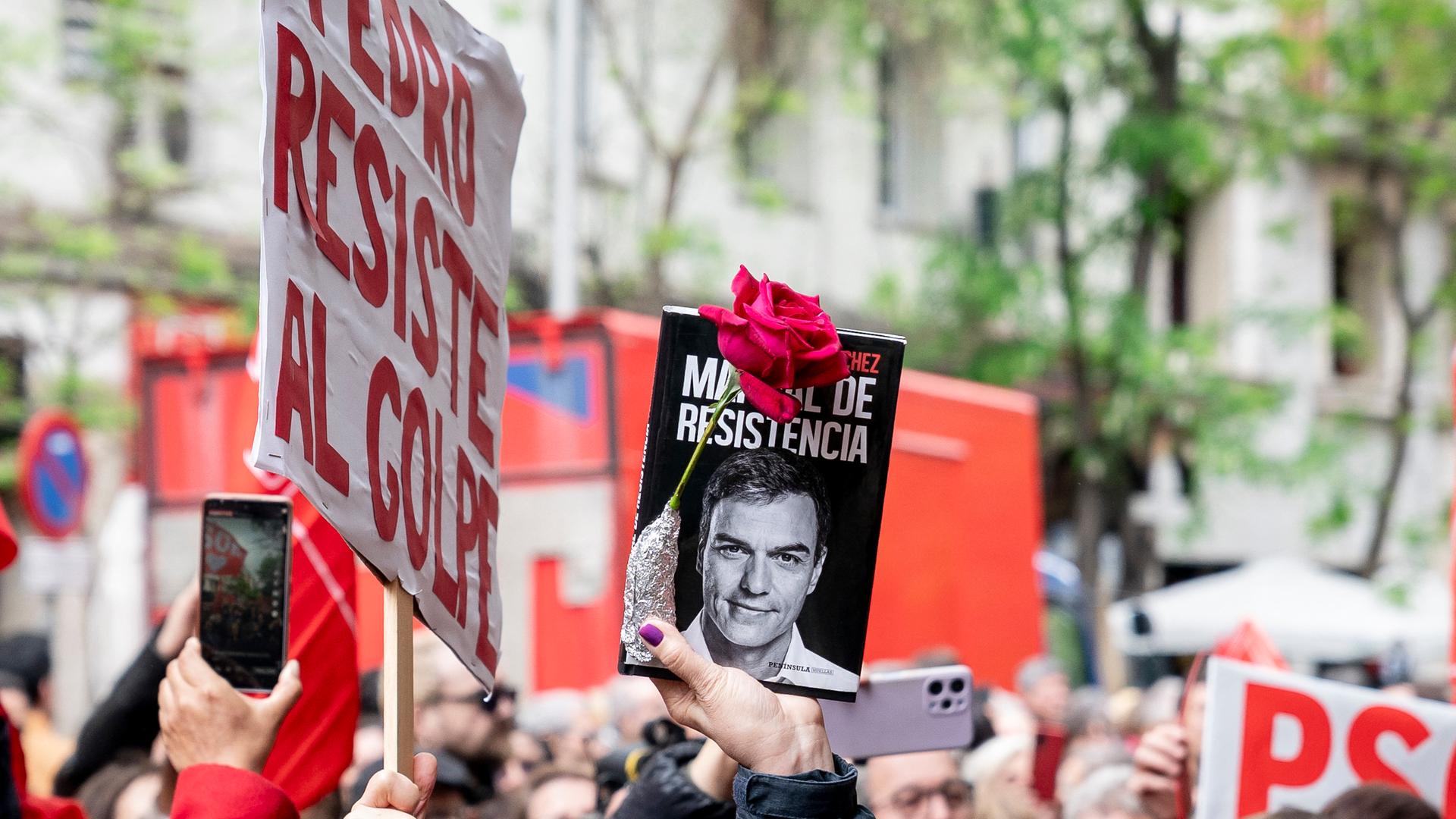 Solidaritäts-Demonstration für den spanischen Ministerpräsidenten Sanchez in Madrid: Eine Frau hält ein Bild, das Sanchez zeigt und eine rote Rose in die Höhe. Aufnahme vom 27.04.2024.
